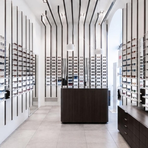 Full interior shot linear slat wall eyewear rack system inside minimalist modern optical retail boutique