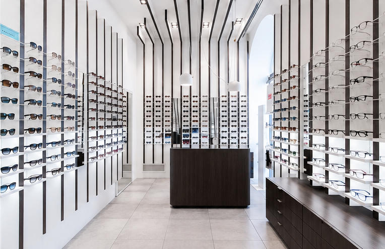 Full interior shot linear slat wall eyewear rack system inside minimalist modern optical retail boutique